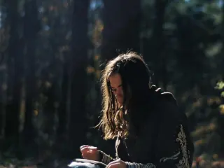 Woman writing in a journal in a sunlit forest