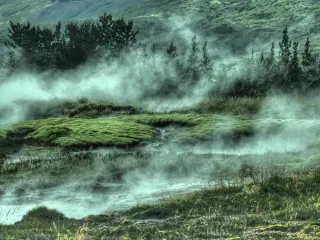 Steam rising across a green geothermal landscape